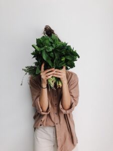 Woman hiding behind dark leafy greens