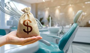 A hand holding a money bag in front of teal dental chair