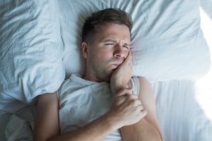 Man lying awake in bed with a toothache